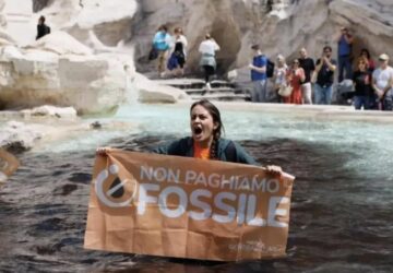 Mulher com faixa contra combustíveis fósseis na Fontana di Trevi, em Roma