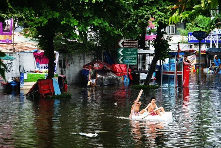 Pessoas em um barco improvisado no meio de um local inundado devido as mudanças climáticas