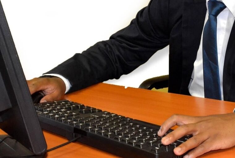 Homem negro de terno como mãos no teclado de computador