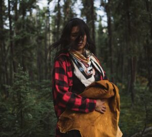 Mulher com roupas coloridas diante de floresta